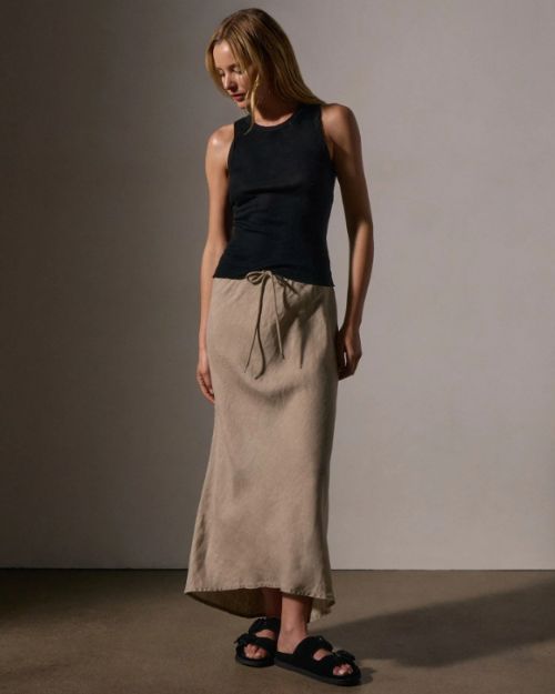  Model in a fitted black cotton cashmere tank top and tan skirt, showcasing a lightweight, soft ribbed fabric.