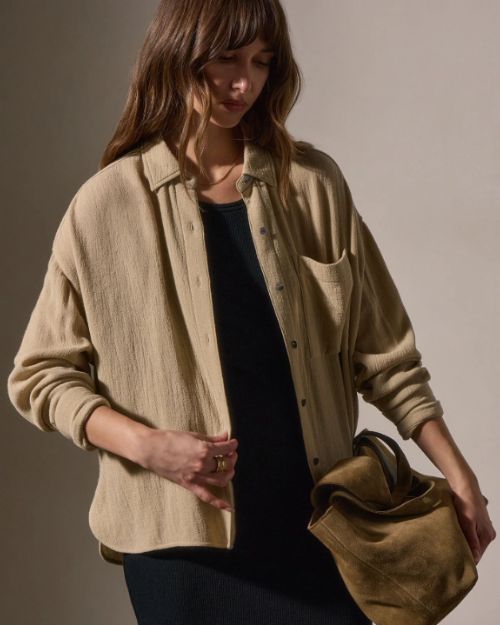 Model wearing a wool blend button-up shirt and a black skirt, posing against a neutral background.
