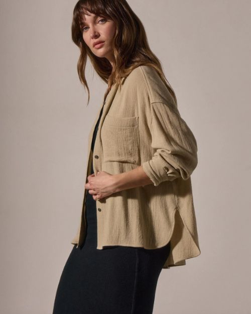 A model wearing a wool blend button-up shirt and a black skirt poses confidently.