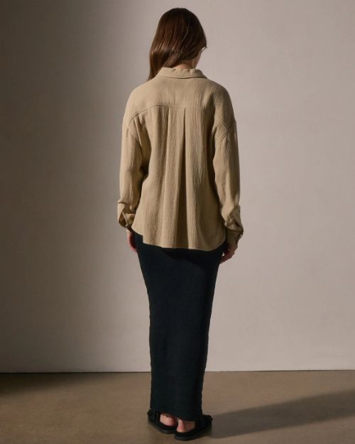 Back view of a woman in a long skirt and a wool blend button-up shirt, showcasing a stylish and casual outfit.