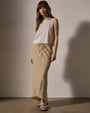A model showcases a white tank top and a bias cut drawcord skirt made from a wool blend.
