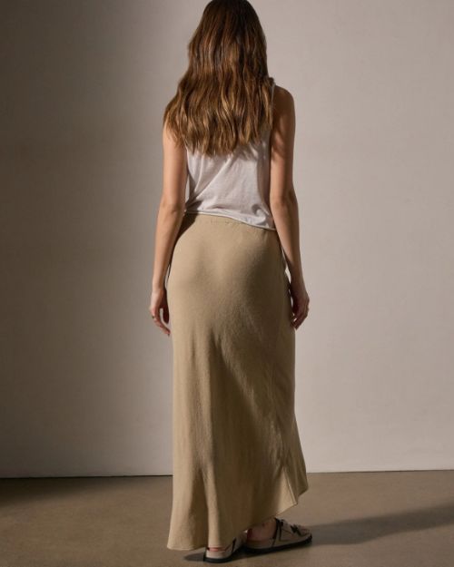 Back view of a woman in a wool blend bias cut drawcord skirt, showcasing its flowing design and elegant silhouette.