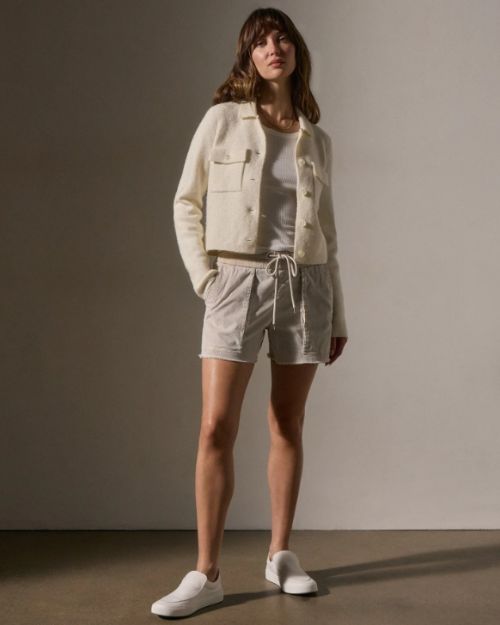Model wearing ivory sweater knit jacket paired with shorts, showcasing a casual yet stylish outfit.