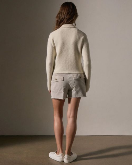 Back view of a woman wearing a stylish ivory sweater knit jacket and shorts, highlighting a casual look.