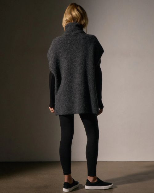  Woman's back view wearing a waffle knit funnel neck tunic paired with black leggings, highlighting a relaxed style.
