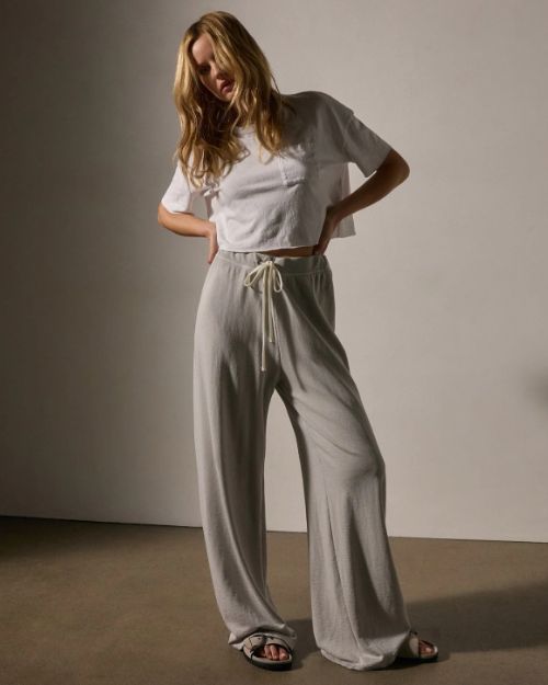 A model wearing a white t-shirt paired with grey wide-leg sweatpants, showcasing a casual and comfortable outfit.