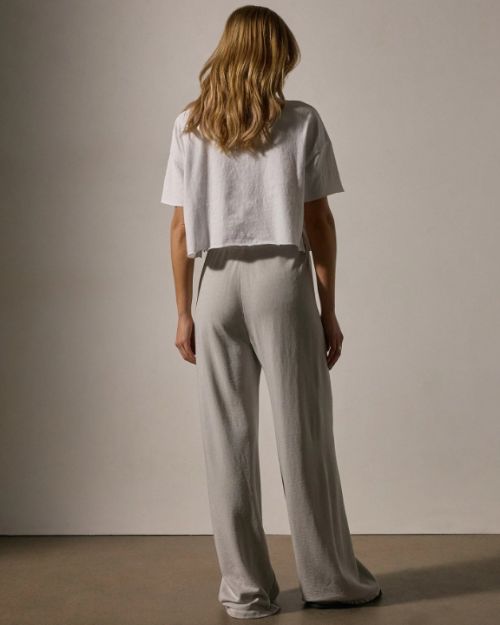 A back view of a model wearing a white t-shirt paired with wide-leg sweatpants, showcasing a casual and comfortable outfit.