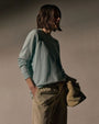 A woman wearing a fresco color boyfriend raglan sweatshirt and pants, standing casually.