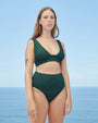 Model wearing Multi Straps Swimsuit Top in pine green in front of ocean backdrop.