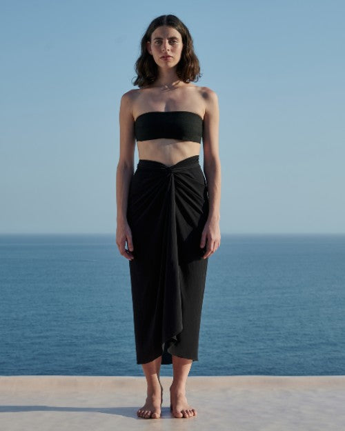 Model wearing Panneaux Cover-Up in black in front of ocean backdrop.