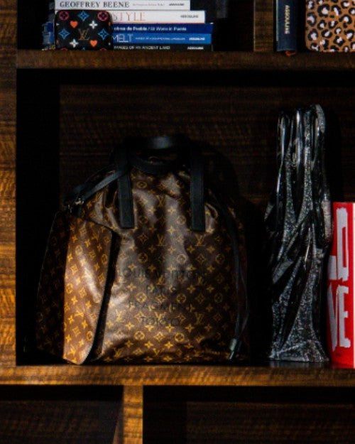 Split Cabas Light Bag placed on dark wood bookshelf next to other Louis Vuitton products.
