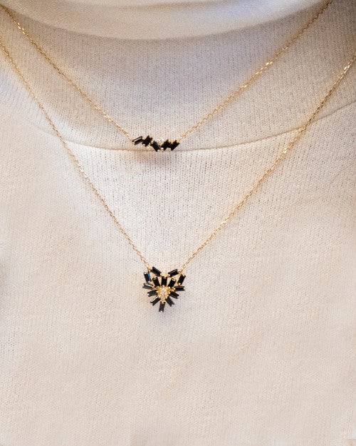 Dainty gold necklace with black sapphires and white diamonds shaped in a zigzag line.