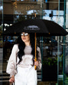 Woman posing in front of The Post Oak Hotel lobby doors with The Post Oak Umbrella.