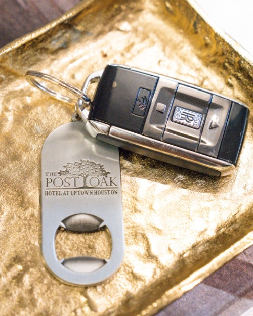 Key with Post Oak Bottle Opener Keyring attached placed in gold tray.