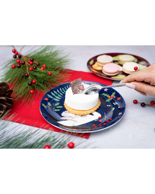 Woman taking a bite of dessert off of plate on festive table. 
