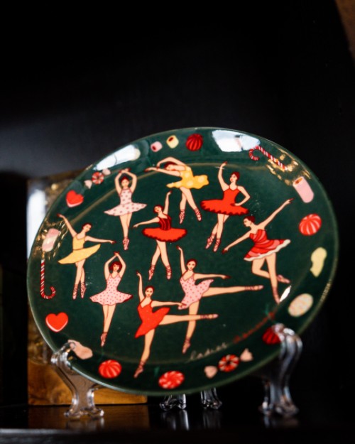 Karen Mabon green ballerinas dancing plate displayed on black table.