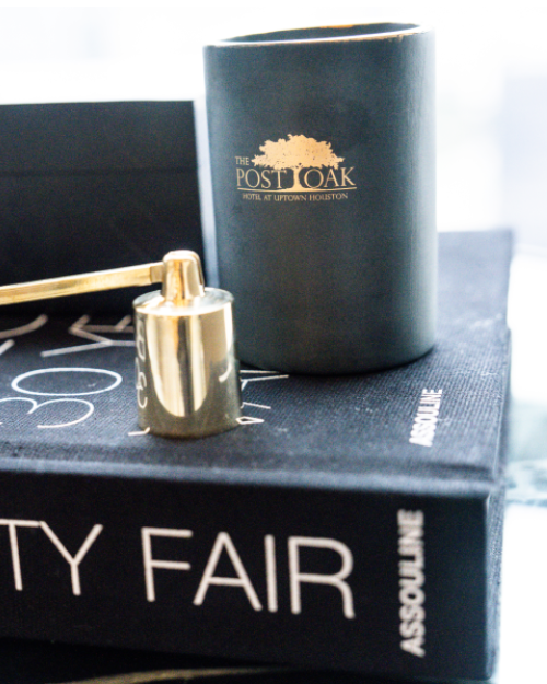 The Post Oak Black and Gold Candle placed on top of Vanity Fair coffee table book.