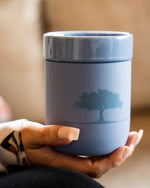 Close up of woman holding Blue Ceramic Mug from The Post Oak while sitting on a couch.