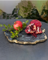 Pomegranates placed on top of Kiva Platter on a black surface. 