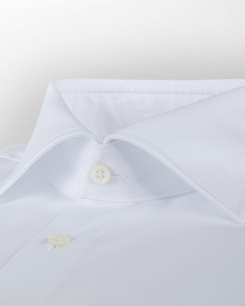 A zoomed in view of a white button-down shirt with black buttons. The background is grey.