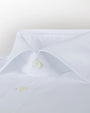 A zoomed in view of a white button-down shirt with black buttons. The background is grey.