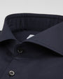 A zoomed in view of a navy button-down shirt with black buttons. The background is grey.