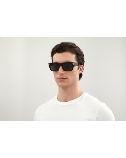 Model wearing Unapologetic Unisex Sunglasses in black in front of white background. 