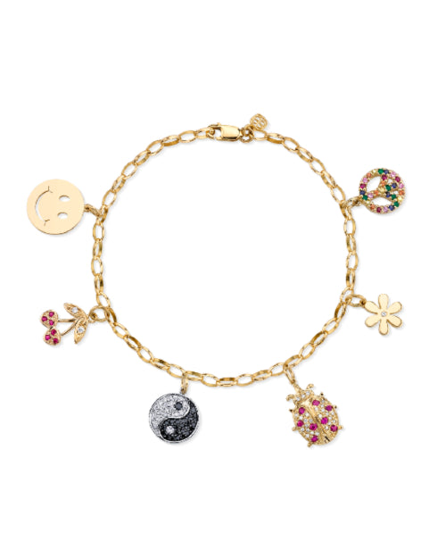 Gold bracelet with multiple charms in front of white background. 