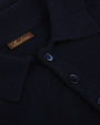 A close-up image of three navy buttons on a navy collared polo-shirt, with a rectangular brown tag and the word "STENSTRӦMS" printed on it.