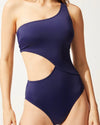Model wearing navy one shoulder, one piece swimsuit with right rib cutout. 