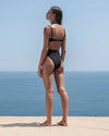 Model turned away from camera to show back of swimsuit bottom.