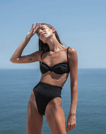 Model wearing Crepe Highleg Swimsuit Bottom in black with matching top.