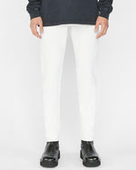 Model wearing white jeans with grey sweater and black boots in front of white background.