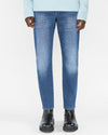 Model wearing L'Homme Slim Crop Jeans in denim color with blue sweater and black boots.