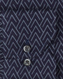 Fabric with a grey arrowlike triangular pattern, and a pocket with two black buttons. 