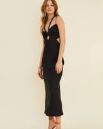 Model wearing long black halter dress with cutouts below the chest and on the ribs. 