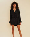 Model wearing black mini shirt dress with long sleeves and deep v-neck. 