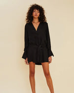 Model wearing black mini shirt dress with long sleeves and deep v-neck. 