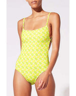 Model wearing bright yellow one-piece swimsuit with pineapple tile.