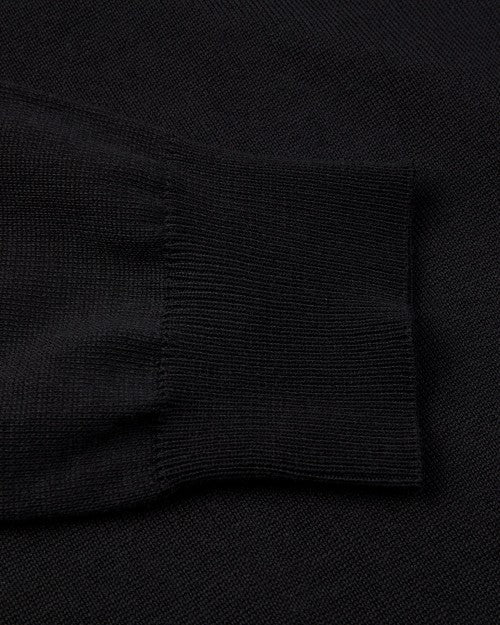 A close-up view of a long-sleeve shirts wrist cuff placed on the black shirt fabric. 
