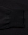 A close-up view of a long-sleeve shirts wrist cuff placed on the black shirt fabric. 
