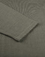 A close-up view of a long-sleeve shirts wrist cuff placed on the green shirt fabric. 