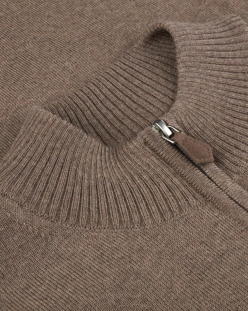 A close-up view of a brown sweaters' neckline cuff with a brown leather zipper. 