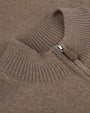 A close-up view of a brown sweaters' neckline cuff with a brown leather zipper. 