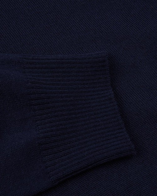 A close-up view of a navy sweaters' ribbed wrist cuff against the navy fabric. 