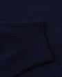 A close-up view of a navy sweaters' ribbed wrist cuff against the navy fabric. 