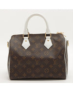 Dark brown Louis Vuitton bag with iconic pattern, white handle, and gold hardware accents. 