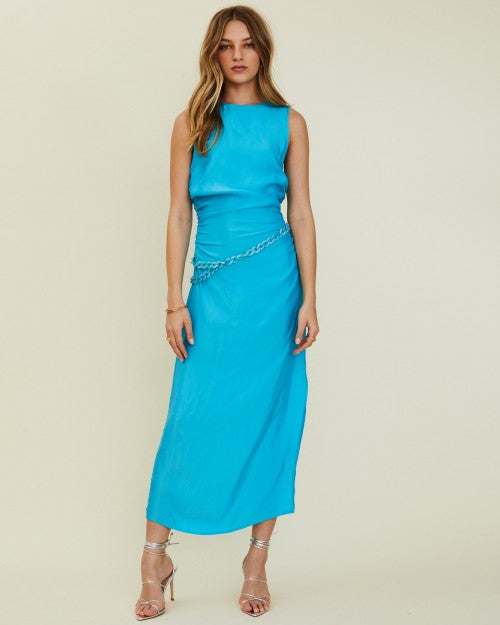 Model wearing a vibrant, turquoise, sleeveless, maxi dress with waist chain.