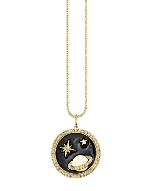 Gold necklace with circle charm of saturn and two bright stars. 
