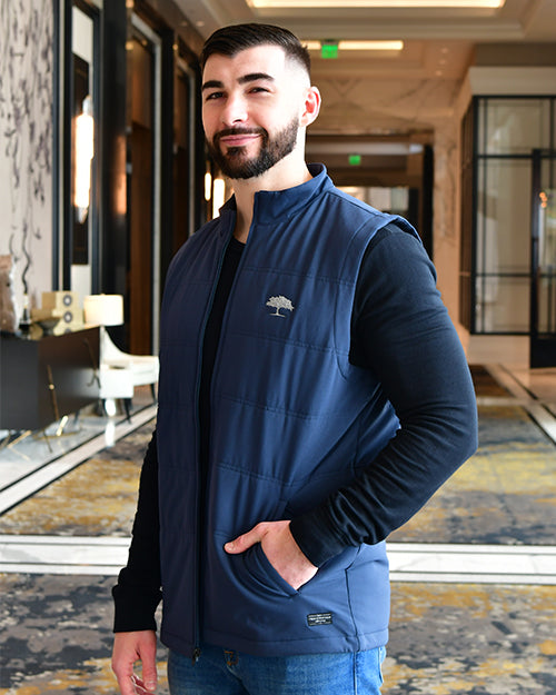 Man wearing indigo puffer vest with embroidered Post Oak tree in Post Oak Hotel.